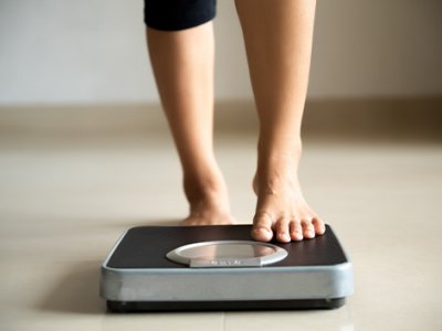 A woman's lower legs stepping onto weighing scales.